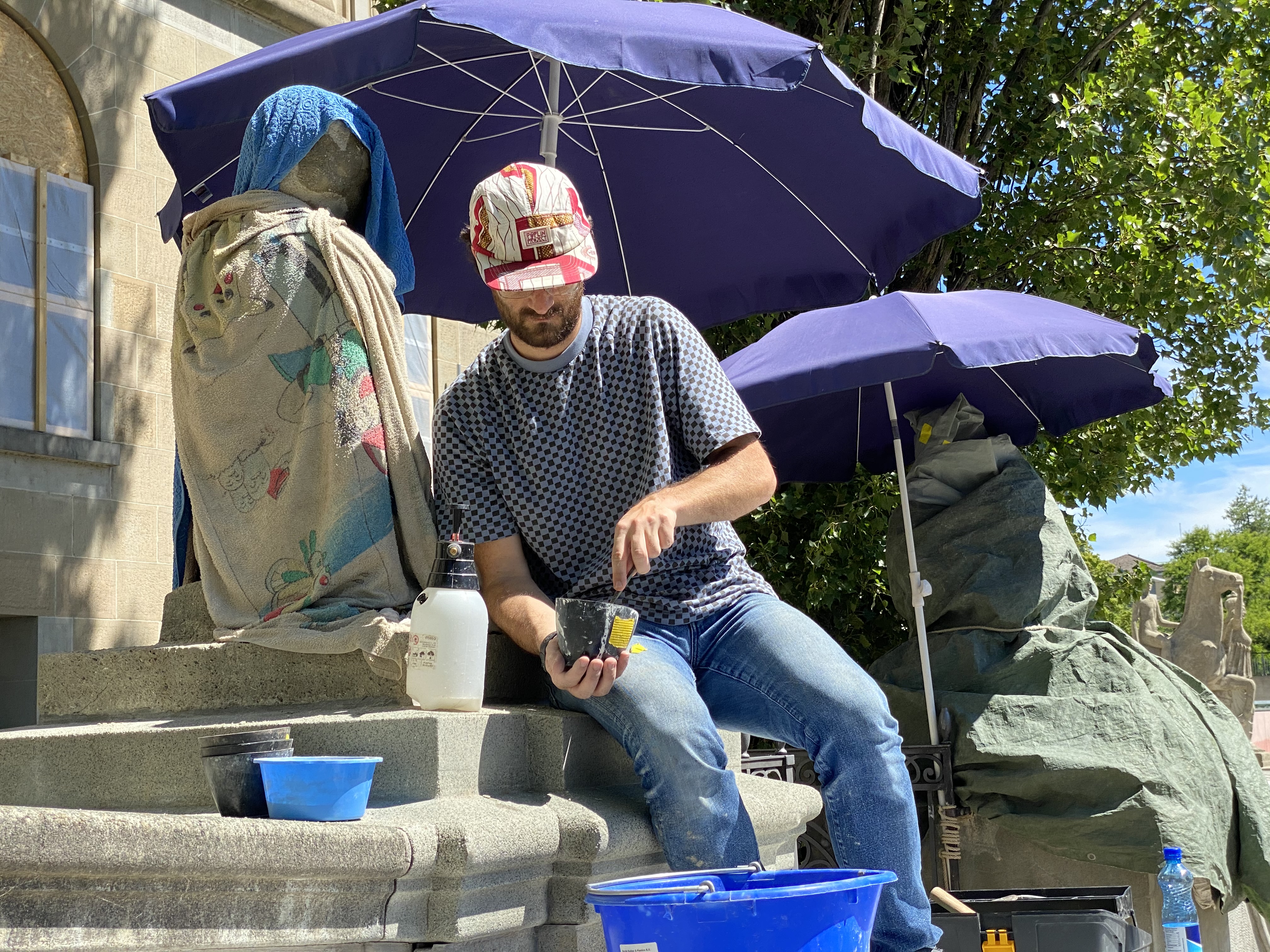 Nach Perkussion und Festigung mit Harz werden die Oberflächen der Skulpturen mit mineralischem Mörtel geschlossen und mangelhafte Stellen aufmodelliert. Der Mörtel ist im Farbton und in der Körnung dem jeweiligen Stein angepasst. (Bild: Kniendes Mädchen am Eingang Künstlergasse der UZH, UZH).