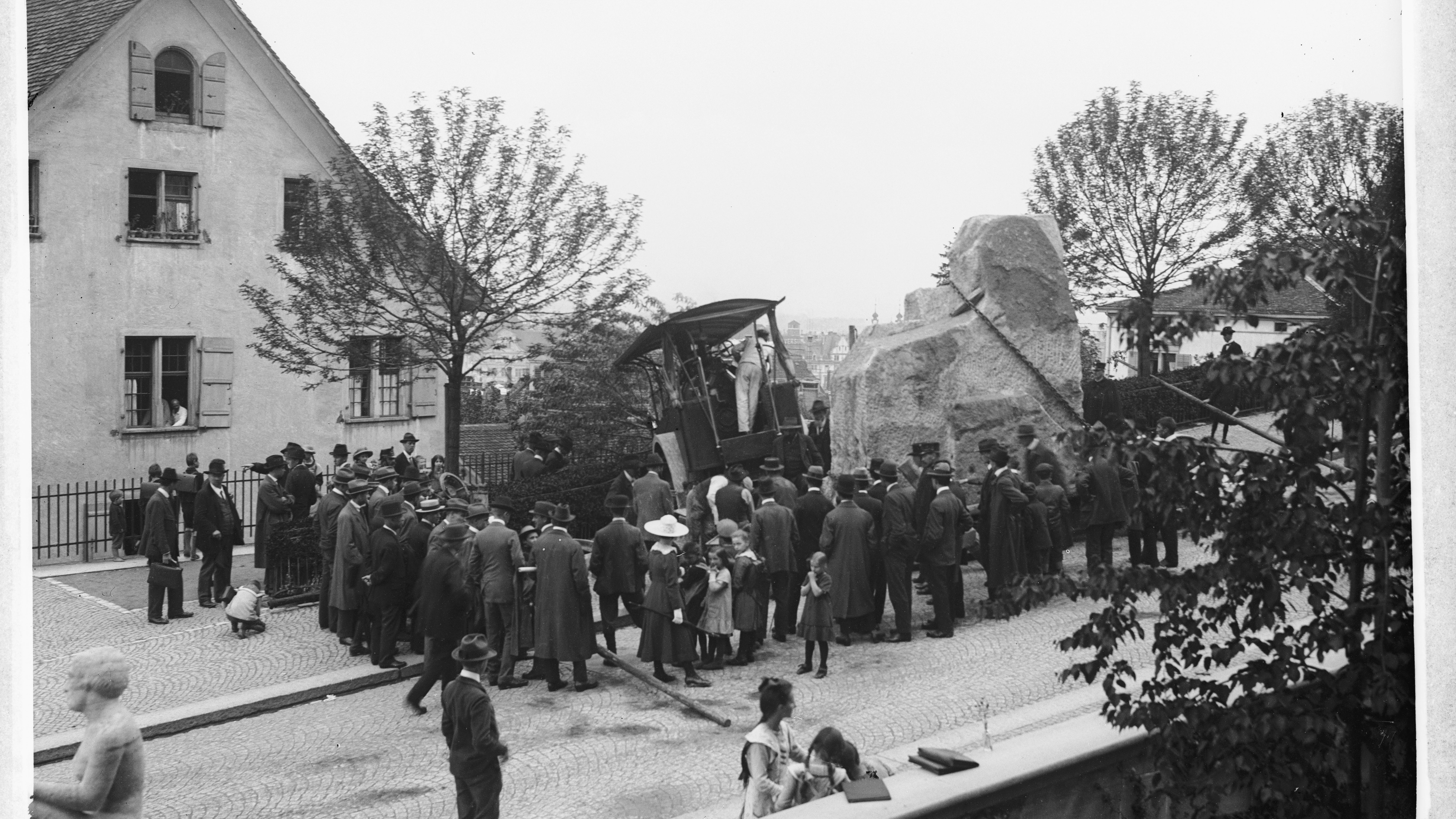 Die Dampfwalze mit dem Kalkstein für die Skulptur ist bei der Anlieferung unter der hohen Last umgekippt und die Böschung an der Künstlergasse hinuntergerollt, was eine grosse Zahl an Schaulustigen angezogen hat (Bild: Archiv Kantonaler Denkmalschutz).