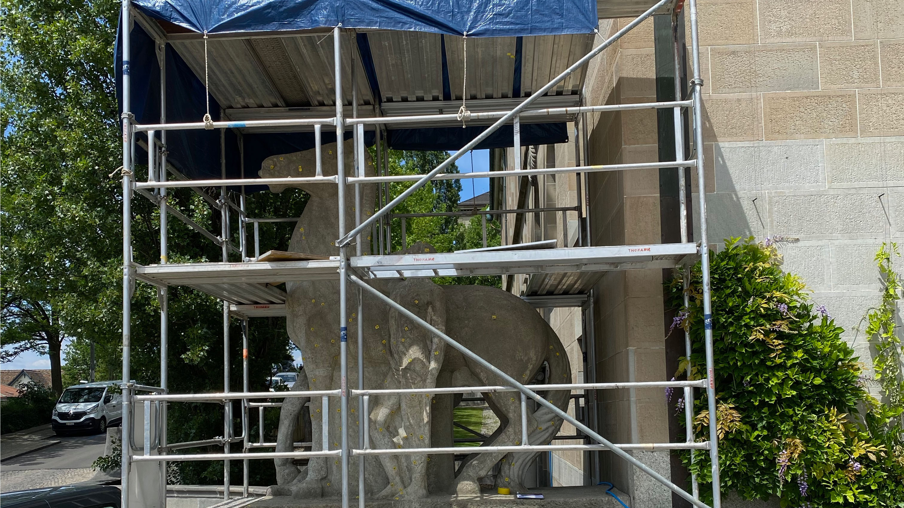 Die erste Skulptur, die über den Sommer 2020 mit einem Restaurationsgerüst eingekleidet worden ist, steht am Eingang Künstlergasse der UZH. Otto Kappeler hat sie zwischen 1914 und 1919 direkt am vor Ort gehauen. Sie zeigt einen älteren Herrn, der von einem Dämon behindert wird, auf ein Pferd aufzusteigen (Bild: UZH).